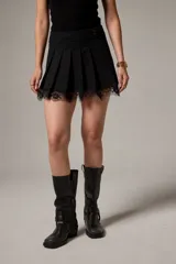 Minifalda negra de algodón con diseño plisado y detalle de encaje transparente en el ruedo.