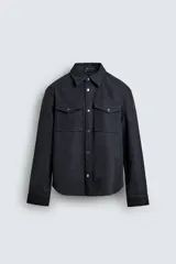 Sobrecamisa de corte relajado confeccionada en tejido efecto piel. Presenta cuello solapa, cierre frontal con botones metálicos, mangas largas con puños abotonados y bolsillos de plastrón con solapa en el pecho.