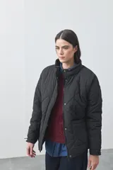 Campera acolchada de nylon color negro, con cuello alto, cierre frontal y botones a presión. Presenta un diseño de rombos y forro interior suave.