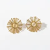 Par de caravanas doradas con forma de sol y centro de piedra blanca.