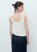 Top de punto fino color blanco, con cuello en V, sin mangas y diseño entallado.