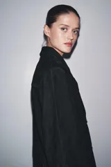 Chaqueta de ante negra con cuello solapa de muescas y manga larga. Tiene bolsillos con solapa en delantero y cierre frontal con botones.