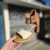 Sandalias de cuero color suela y beige, con plataforma de madera, taco ancho y doble tira con hebillas metálicas en el tobillo. Cuentan con cierre trasero.