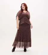 Falda midi de tul con estampado de corbatas, cintura elástica y diseño con volados. Presenta un forro más corto que crea un efecto de transparencia en el ruedo.