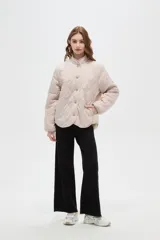 Campera de diseño acolchado con patrón capitoneado, cuello mao y cierre frontal con botones. Presenta mangas largas y un corte recto.