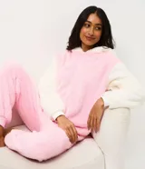 Pijama enterizo tipo mono confeccionado en tejido fleece de tacto suave y peludo. Presenta cierre frontal con cremallera y capucha integrada con diseño de la cara de Hello Kitty, incluyendo orejas en 3D y un lazo rojo aplicado.