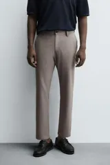 Pantalón chino de corte slim fit, confeccionado en tejido elástico. Presenta bolsillos frontales, bolsillos traseros de vivo con botón y cierre frontal con cremallera y botón.