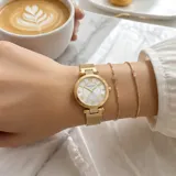 Reloj analógico de mujer con caja redonda dorada, esfera blanca con números romanos y malla de acero tipo milanesa dorada.