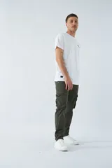 Pantalón cargo color beige, corte slim, con cierre y botón en la cintura, pasacintos, bolsillos cargo con botones y sin puños.