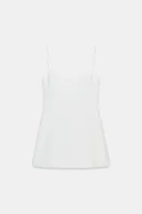 Mono corto blanco, con escote redondo, tirantes finos ajustables y abertura frontal.