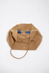 Bolso shopper grande de Bimba y Lola, confeccionado en serraje de piel vacuna con acabado de ante color marrón. Presenta doble asa de hombro y detalle de logo metálico de la marca en la parte inferior.