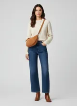 Bolso de hombro tipo media luna, color marrón cuero, confeccionado en ante (cuero). Presenta un cierre superior de cremallera y una correa de hombro ancha.