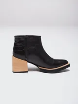 Botineta de cuero color suela, con diseño de punta fina y puntera texturizada con efecto reptil. Presenta una suela de madera clara con borde negro y cierre lateral interno.