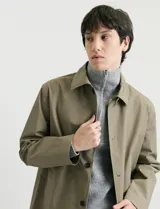 Gabardina clásica de corte recto, color beige, con cuello camisero, cierre frontal de botones y bolsillos laterales. Confeccionada en tejido técnico repelente al agua y al viento.
