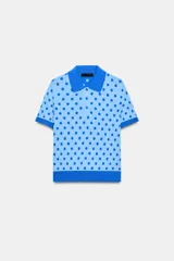 Top de punto celeste con estampado de lunares azules, cuello polo, manga corta y cierre frontal con botones.