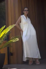 Vestido largo de color blanco, sin mangas, con escote en V y corte holgado con frunce bajo el busto.