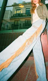 Pantalón de jean de corte recto y tiro medio, con flecos laterales largos de cuero genuino.