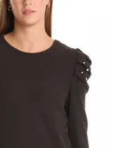 Buzo de tejido soft color gris oscuro, con cuello redondo y mangas largas. Presenta hombros con diseño plisado y detalle de perlas aplicadas.