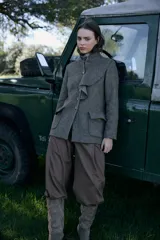 Chaqueta de lana en tono verde oliva con textura jaspeada, cuello mao y detalle de volado frontal. Presenta un corte entallado, bolsillos delanteros con solapa y cierre frontal con botones.