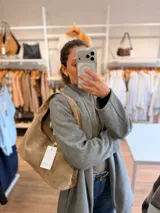 Cartera tipo hobo de diseño flexible y caída natural, confeccionada en material con textura simil gamuza. Cuenta con asa corta integrada para llevar al hombro, cierre superior y bolsillo interior con cierre.