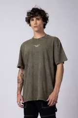 Remera de corte holgado con efecto de lavado ácido en tono gris oscuro. Presenta un pequeño estampado gráfico en el centro del pecho con la inscripción 'ASTRAL ENERGY' y las siglas 'VCP'.