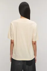 Remera oversize de jersey de algodón color beige claro, con cuello redondo, mangas cortas y estampa frontal de unos labios con un caramelo.