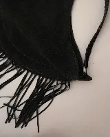 Bolso tipo hobo de gran tamaño en color marrón, confeccionado en gamuza. Presenta un diseño con flecos largos en la parte inferior, cierre superior y una correa trenzada con detalles artesanales.