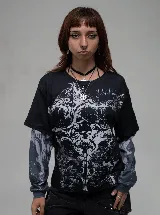 Remera de manga larga con diseño de doble capa, que combina una remera de manga corta negra con estampado gráfico gótico en el frente y mangas largas integradas con estampado abstracto en tonos grises.