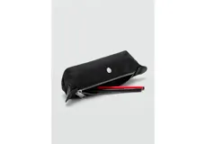 Estuche cilíndrico color negro, con cierre superior de cremallera y detalle de botón a presión plateado en la parte central.