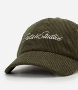Gorra de béisbol con visera curva, confeccionada en tejido de pana (cotelé) color verde oliva. Presenta un bordado frontal con la inscripción 'Future Studios' en color blanco y cuenta con un sistema de ajuste mediante hebilla metálica en la parte posterior.