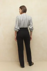 Pantalón negro de vestir, de tiro alto y corte ancho, con bolsillos laterales y cintura elástica.