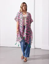 Kimono ligero de poliéster con estampado geométrico en tonos rosa y verde, mangas cortas y terminación con borlas verdes en el ruedo.