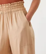 Pantalón pantacourt color beige, con cintura elástica y bolsillos cuadrados aplicados.