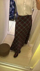 Pollera larga de corte recto con estampado de cuadros en tonos azul, gris y marrón. Presenta un diseño de tiro alto y cierre lateral.