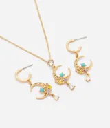 Conjunto de bijouterie color dorado compuesto por un collar de cadena fina y caravanas haciendo juego, con dijes en forma de luna decorados con piedras de colores y detalles brillantes.