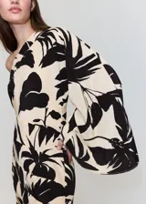 Vestido corto de viscosa con diseño asimétrico de un solo hombro y manga larga abullonada. Presenta un estampado botánico en tonos beige y negro.