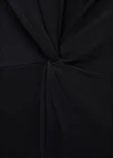 Vestido midi negro sin mangas, con cuello redondo, tirantes anchos y un detalle de nudo drapeado en la cintura.