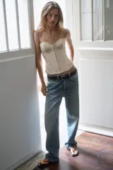 Top estilo corset de color beige, con escote corazón, tirantes finos ajustables y cierre frontal con ganchos metálicos.