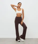 Pantalón deportivo de corte flare, color marrón, con cintura elástica y diseño liso. Presenta una abertura lateral en el bajo.