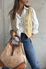 Chaleco beige de gamuza con detalles de nudos decorativos en el frente.