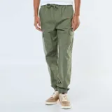 Pantalón cargo de hombre color verde militar, con múltiples bolsillos laterales y puños ajustados elásticos en los tobillos. Presenta cintura elástica con cordón de ajuste.