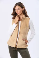 Chaleco de tejido sherpa color beige, con cuello alto y detalles en eco cuero. Diseño sin mangas que proporciona abrigo al torso manteniendo la libertad de movimiento.