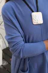 Sweater de punto color celeste, de corte holgado y largo, con mangas largas, cuello redondo y dos bolsillos frontales tipo parche.