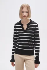 Sweater de punto a rayas horizontales negras y blancas, con cuello en V adornado con pequeños volados y mangas largas.