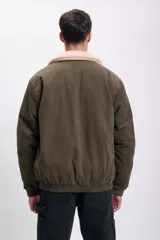 Campera bomber verde de pana con cuello de piel sintética color crema, cierre frontal con cremallera, bolsillos laterales con solapa y puños y cintura elastizados.