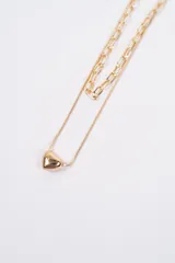 Collar doble de cadena dorada, compuesto por una cadena de eslabones rectangulares y una cadena fina tipo serpiente con un dije de corazón liso.