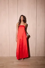 Vestido largo strapless de tafeta color rojo con efecto tornasolado, corte suelto y bolsillos ocultos.