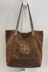 Bolso tipo tote bag de gamuza azul con asas de cuero marrón y bolsillo externo con logo bordado.