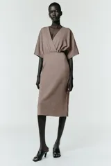 Vestido midi de escote en pico cruzado y manga corta. Presenta detalle de frunces en la cintura y un cinturón integrado con hebilla metálica a contraste.