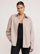 Camisa oversize color beige, con cuello camisero, manga larga y cierre frontal de botones.